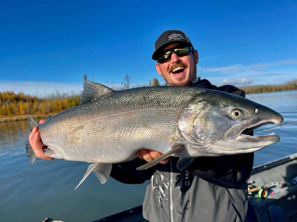 Man holding fish up to camera smiling