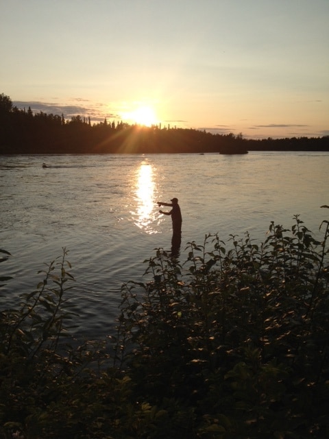 Person fishing in the river at sunset